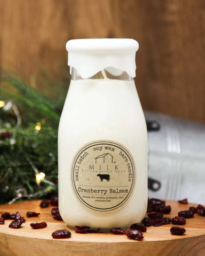 Milk bottle with a label on a wooden board with cranberries, against a wooden background.